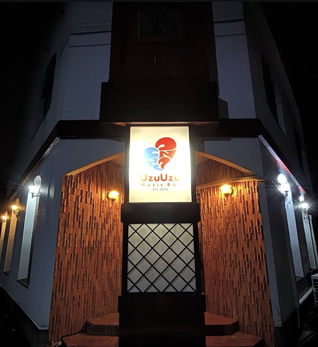 夜のMusic Bar UzuUzuの入り口。赤と青のハートの看板に明かりが灯っている